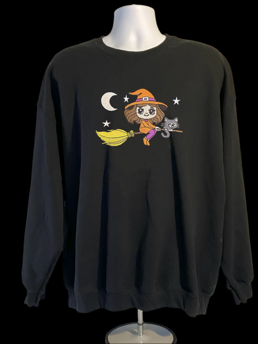 Black sweatshirt with a cartoon witch design on a mannequin against a beige background